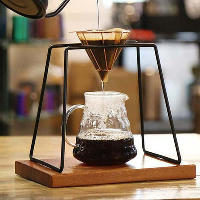 Stainless steel hand brew coffee drip filter holder with coffee dripping into a glass carafe.